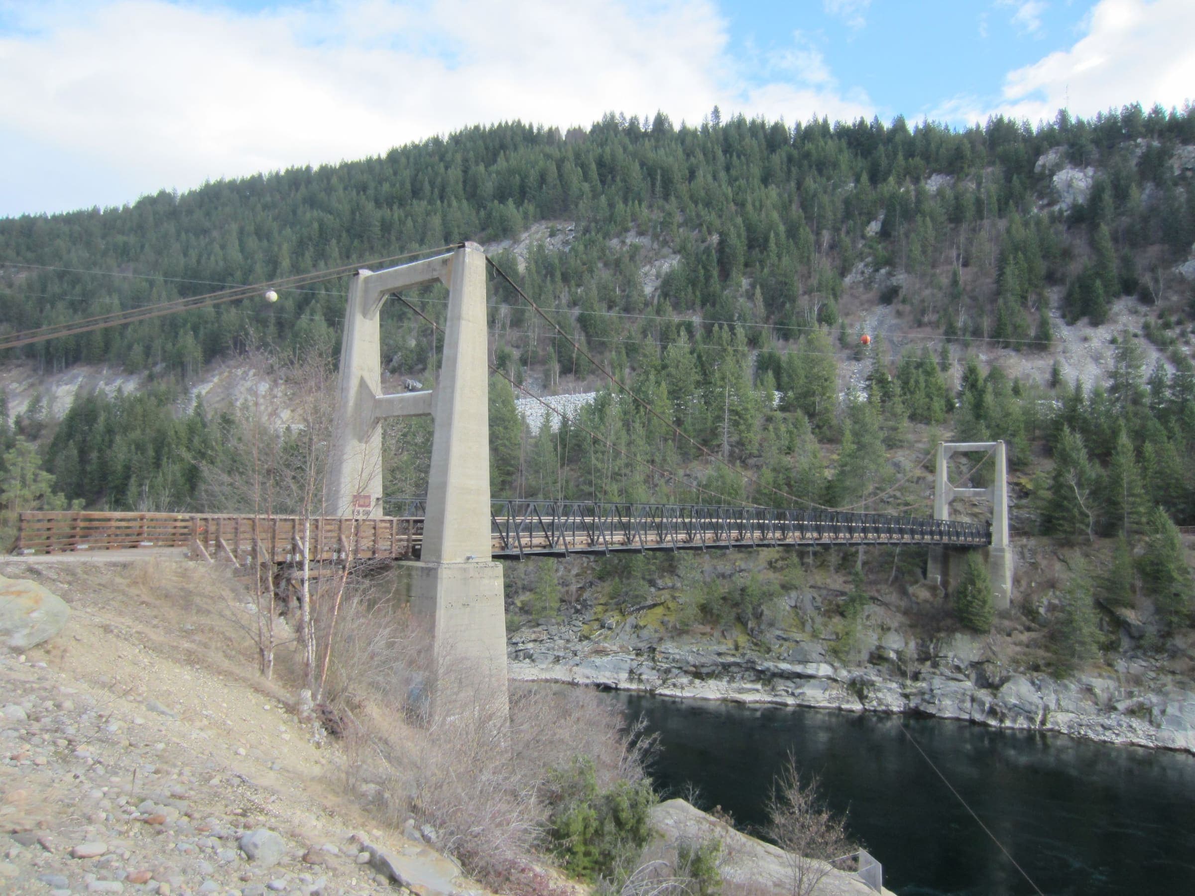Brilliant Suspension Bridge spanning the Kootenay River, with forested ridges behind